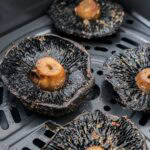 cooked portobello mushrooms in air fryer basket.