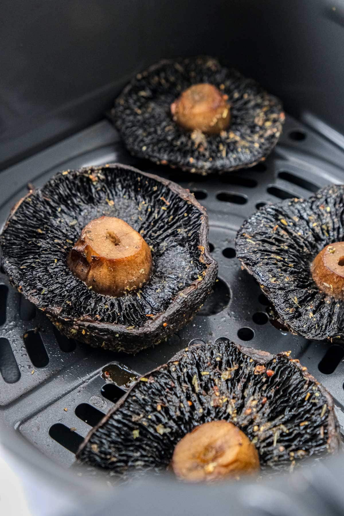 cooked portobello mushrooms in air fryer basket.