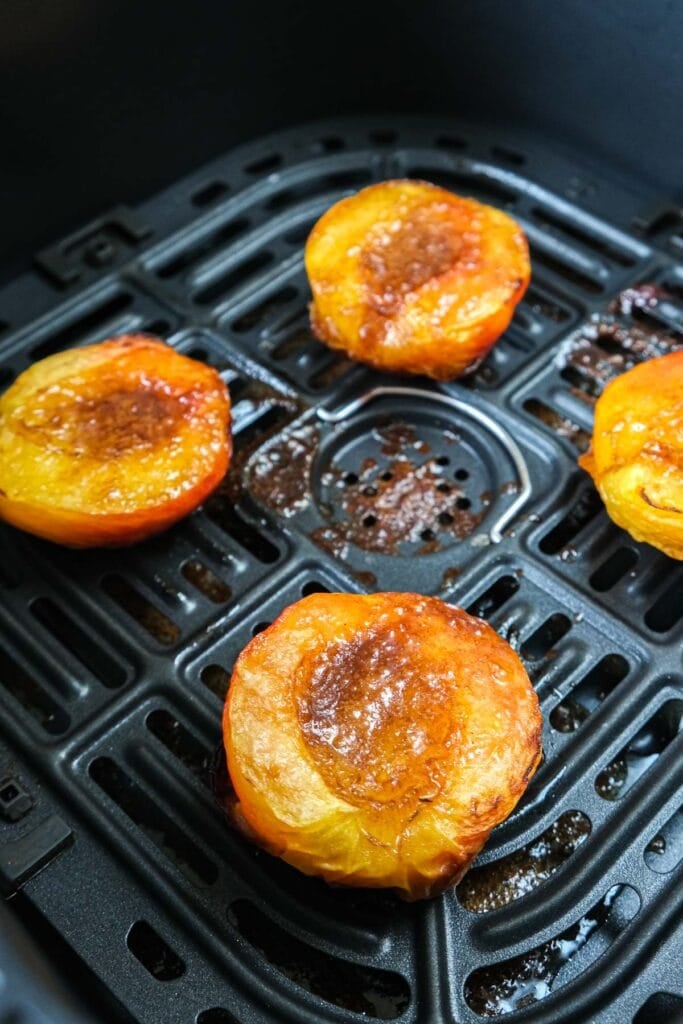 peaches with cinnamon sugar mixture in center in black air fryer.