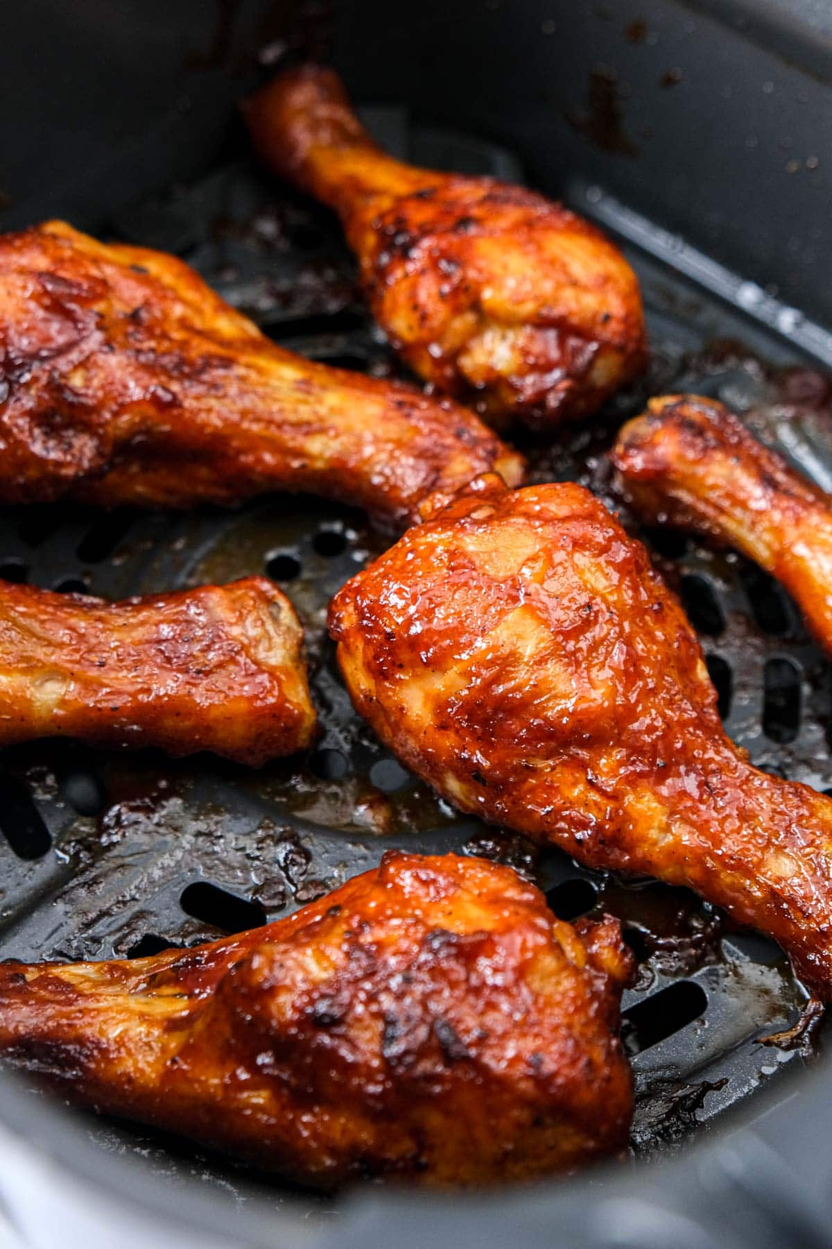 crispy bbq chicken drumsticks in black air fryer basket.