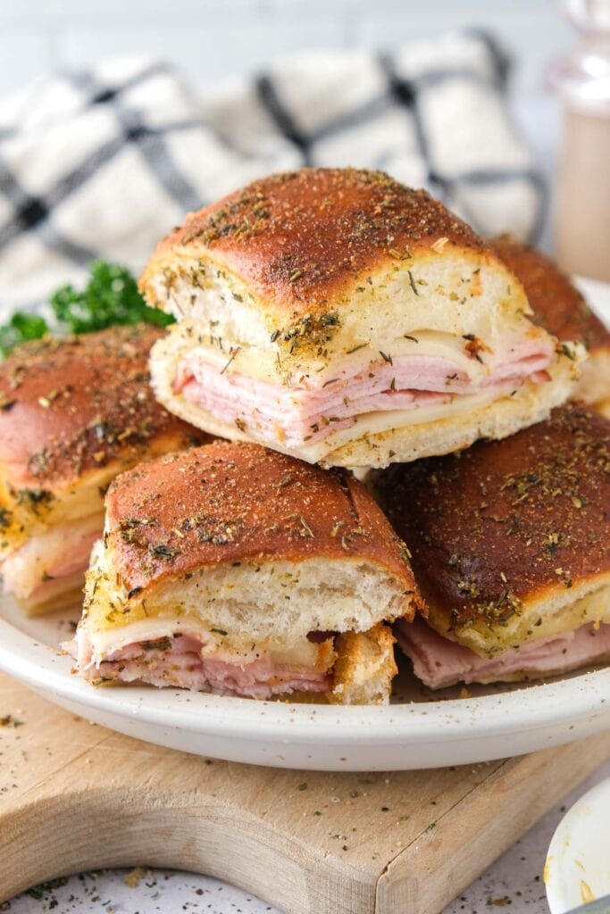 ham and cheese sliders on plate on wooden board.