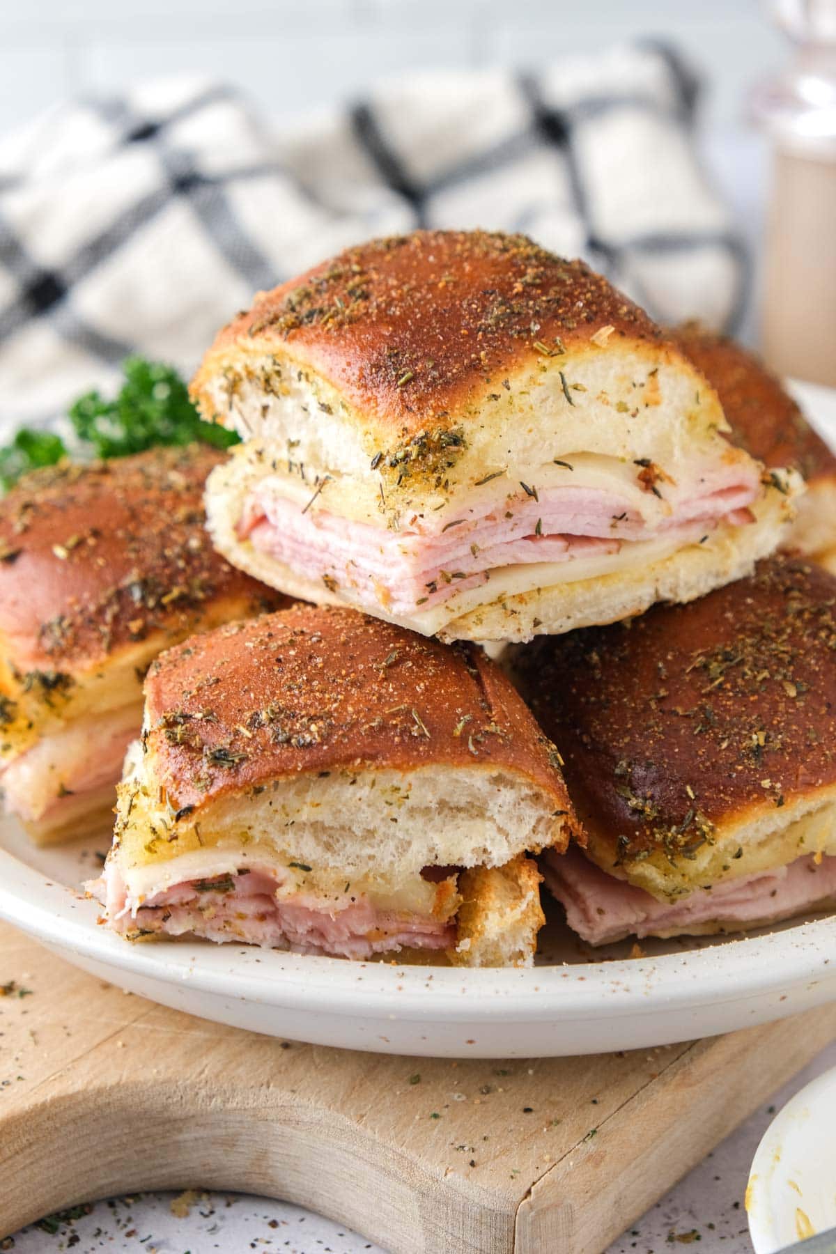 ham and cheese sliders on plate on wooden board.