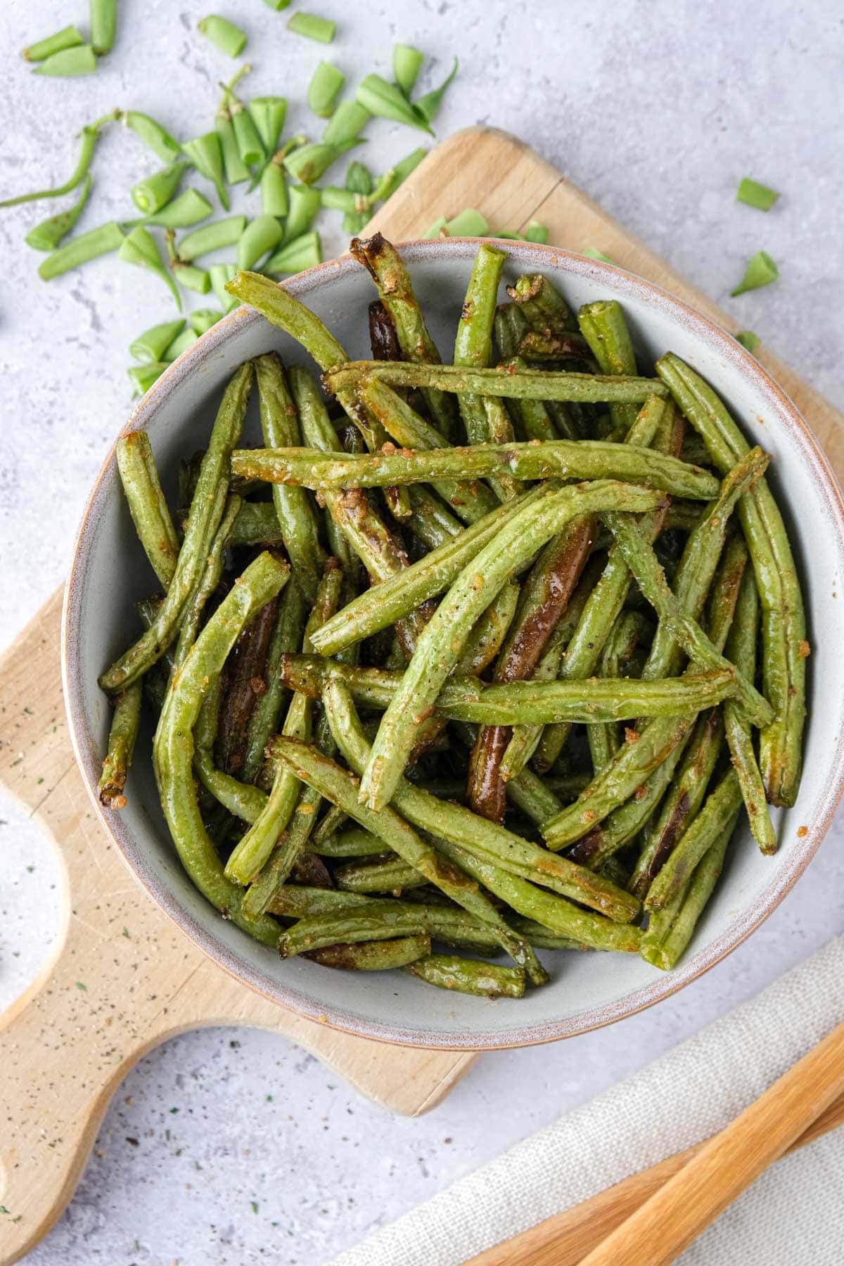 bowl of lemon garlic green beans in wooden cutting board.