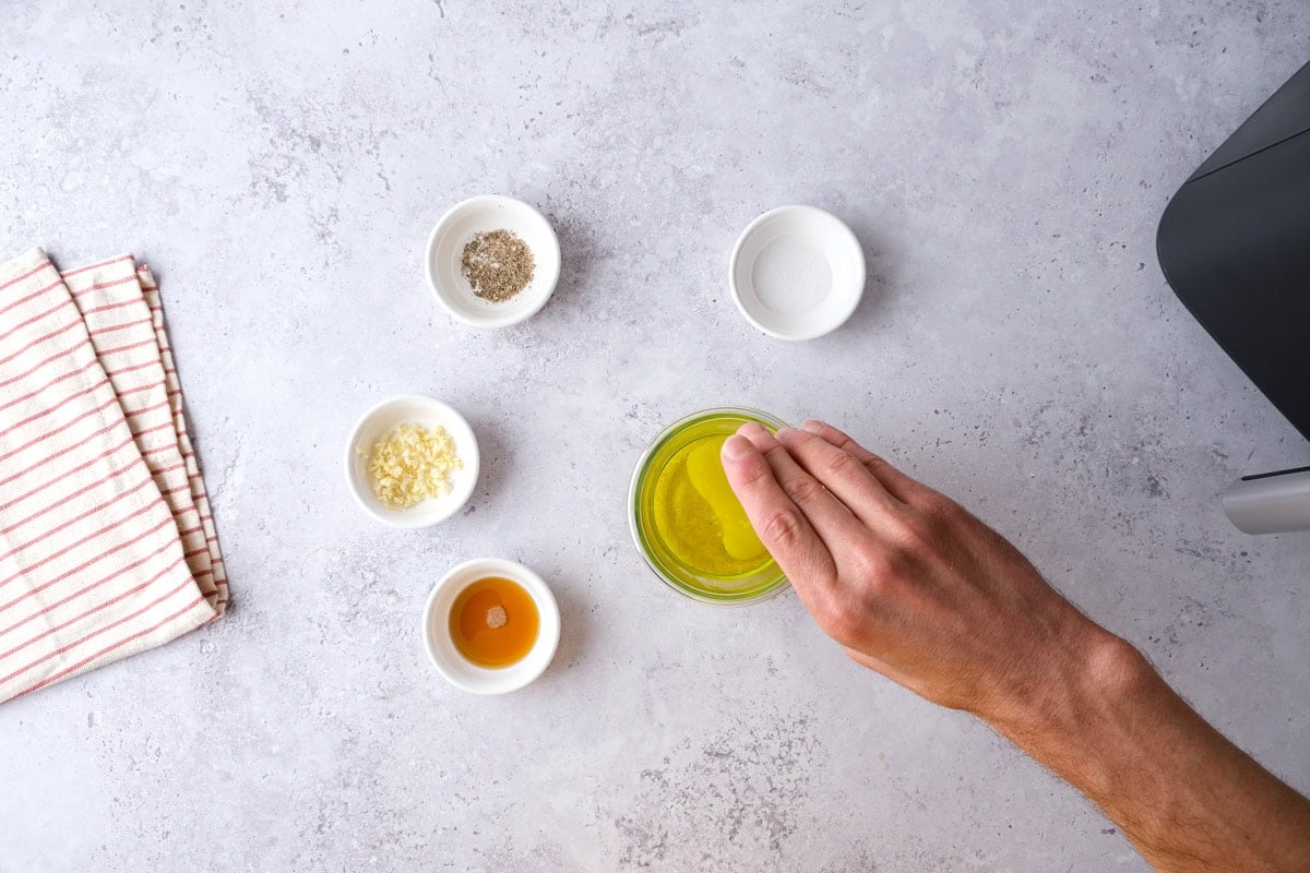 ingredients for dressing including maple syrup, garlic, pepper, and salt in individual containers.