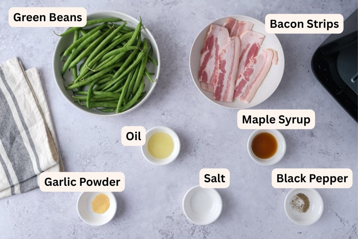ingredients to make bacon wrapped green beans on counter in bowls with labels.