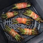 cooked bacon wrapped bundles of green beans in air fryer basket.