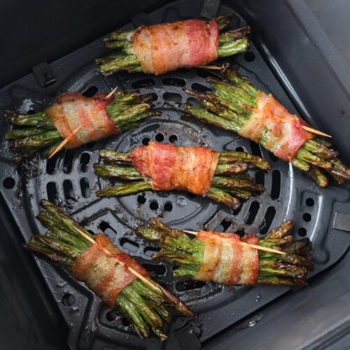cooked bacon wrapped bundles of green beans in air fryer basket.