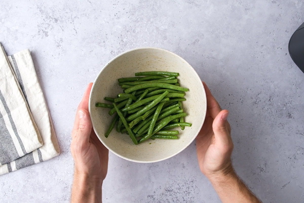 green beans in bowl with seasonings on counter.