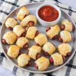 plate of homemade pigs in a blanket with ketchup on plate on dish.