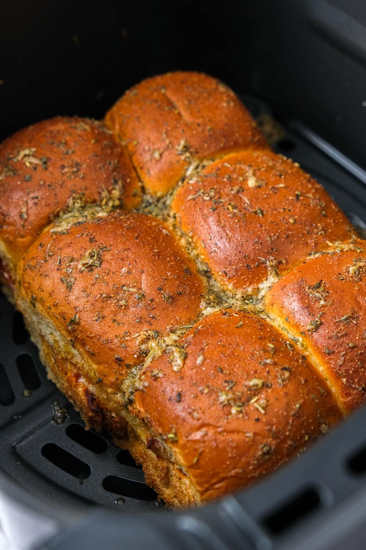 crispy slider buns in air fryer basket covered in seasonings.