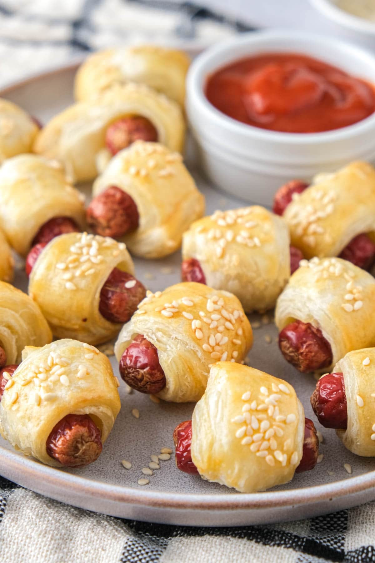 homemade pigs in a blanket on plate with ketchup behind.