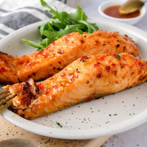sweet chili salmon fillets on plate with salad and fork.