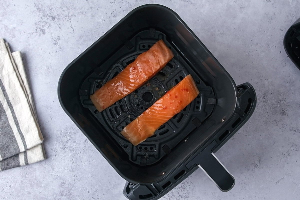 salmon fillets in air fryer basket on counter.
