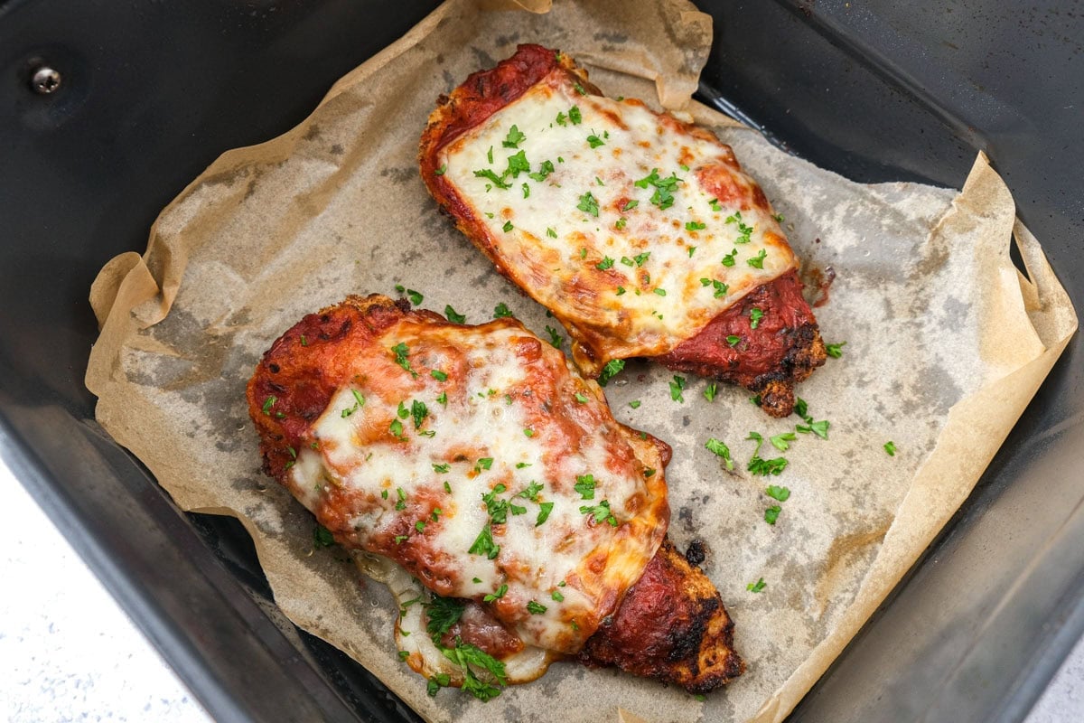 cooked chicken parmesan in air fryer basket.