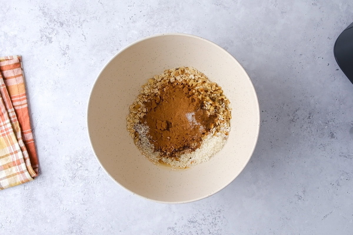 mixing bowl full of cinnamon and oats sitting on counter top.