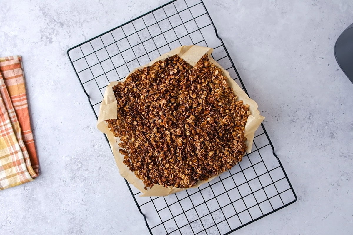air fried granola on parchment paper cooling on wire rack on counter.