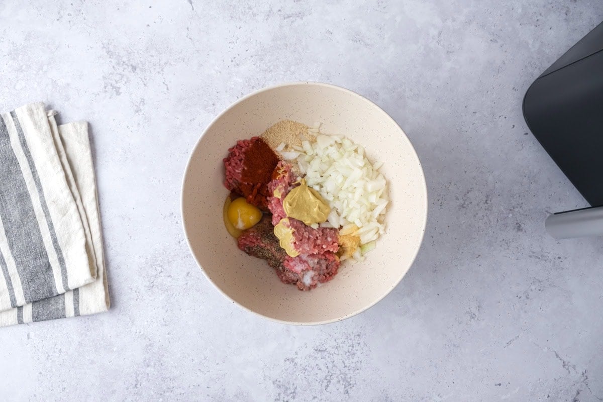 raw ingredients to make meatloaves in bowl on counter.