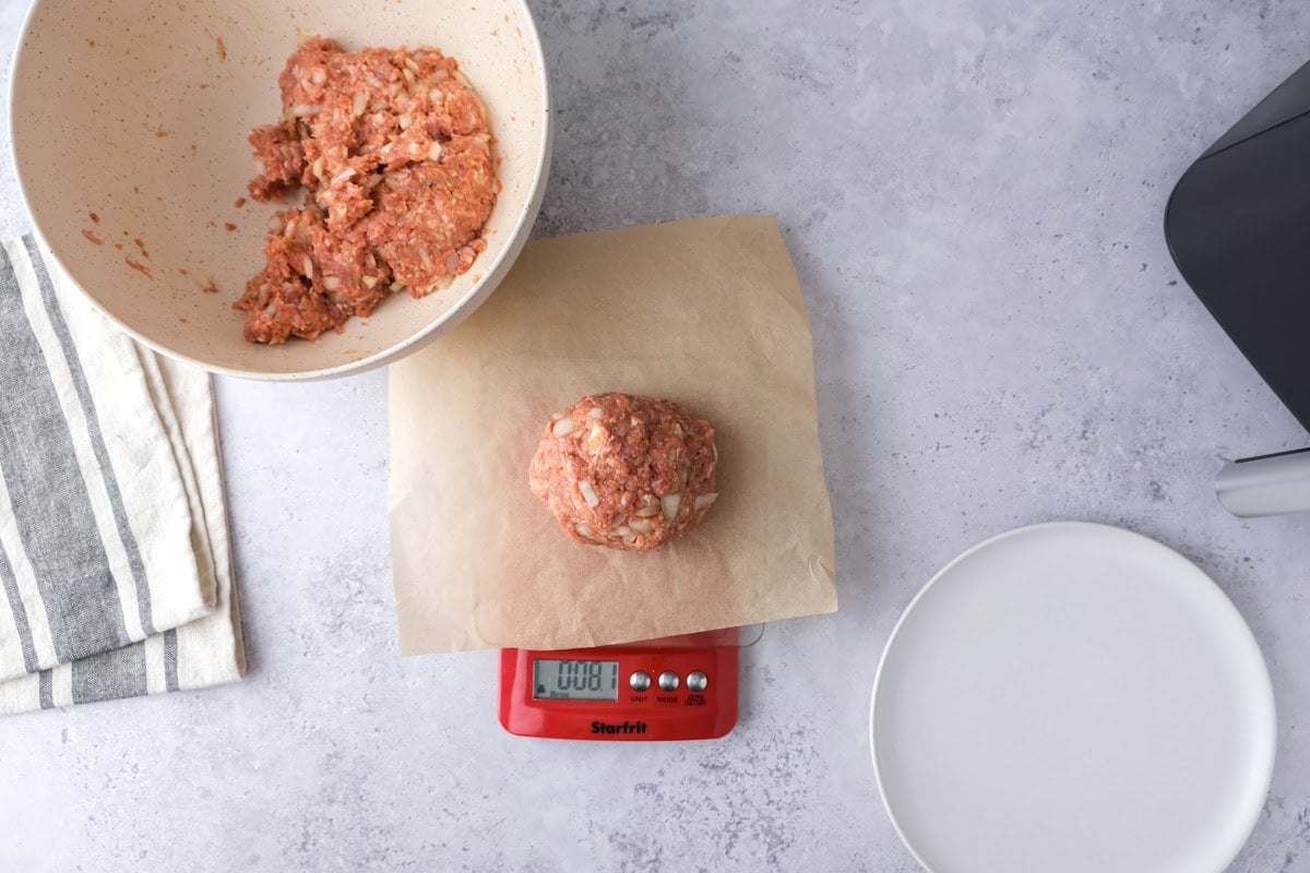 raw meat on parchment paper on a scale with other bowls around.