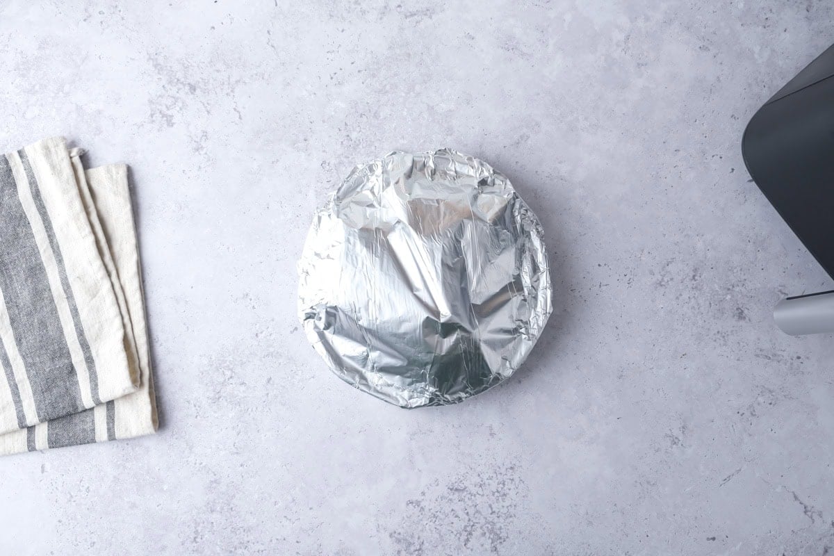 tin foil covering cooked meatloaves on plate on counter.