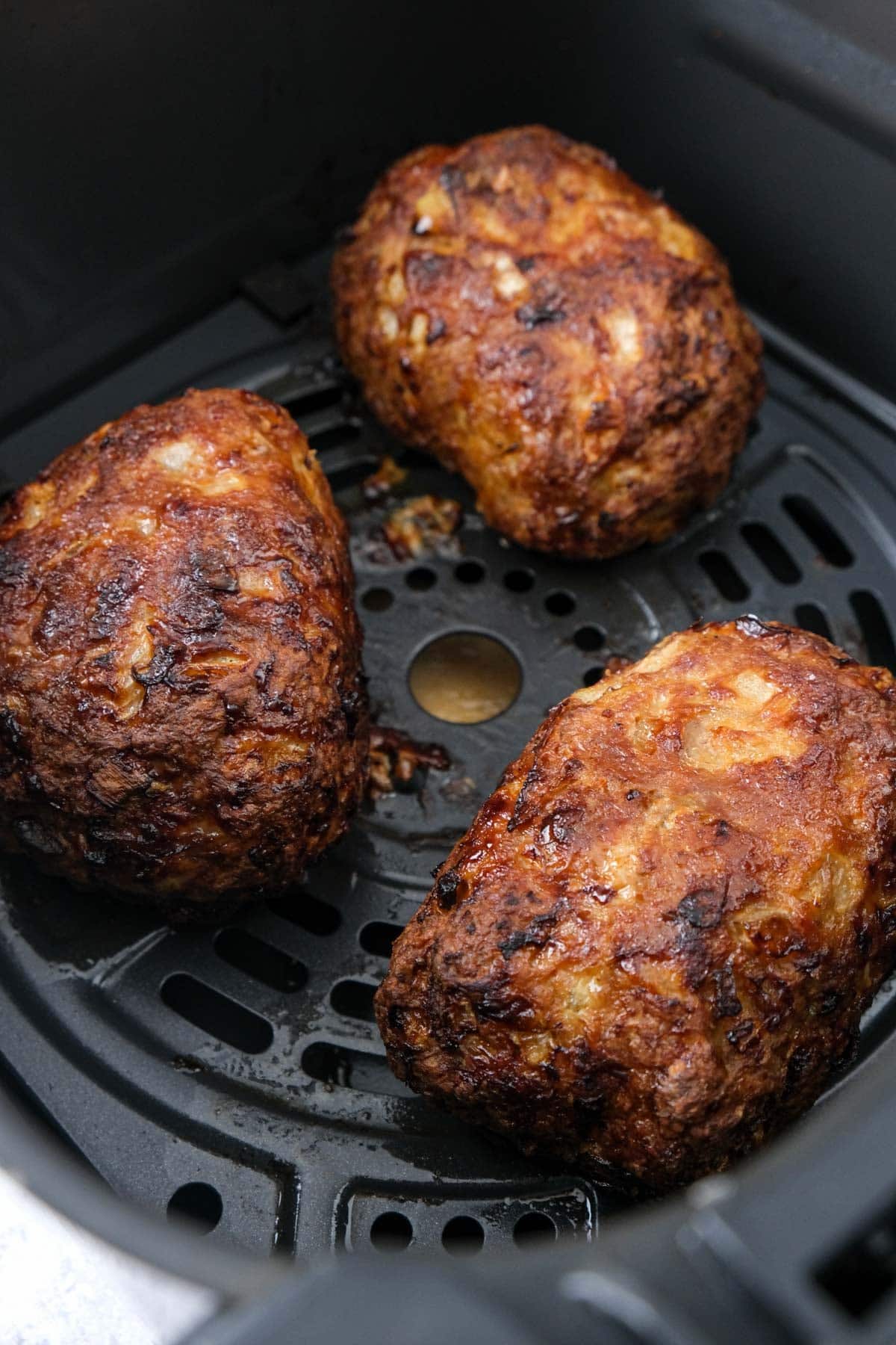cooked mini meatloaves in air fryer basket.