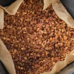crispy sweet granola in air fryer basket on parchment paper.