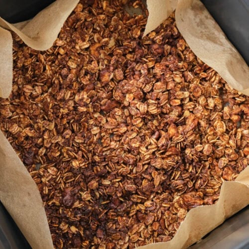 crispy sweet granola in air fryer basket on parchment paper.